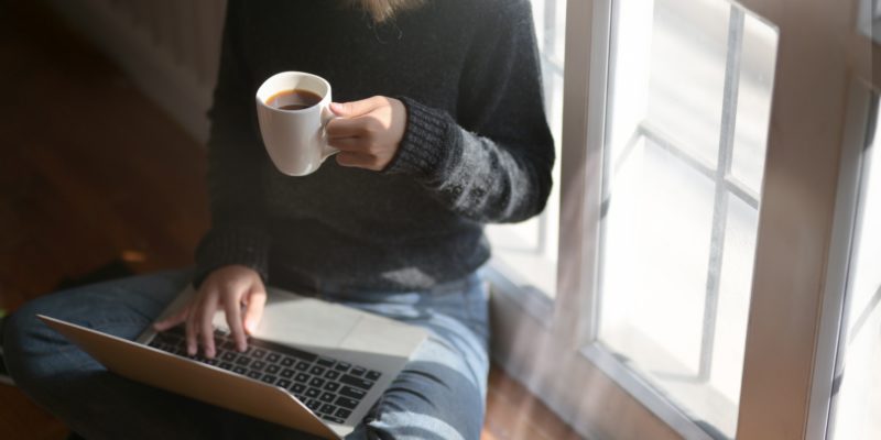 Woman Using Laptop While Holding A Cup Of Coffee 3759083